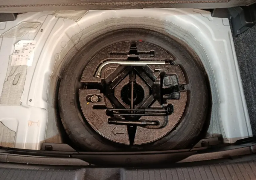 Gros plan sur la roue de secours et les outils de bord dans le coffre d'une Volkswagen Polo blanche 2020.