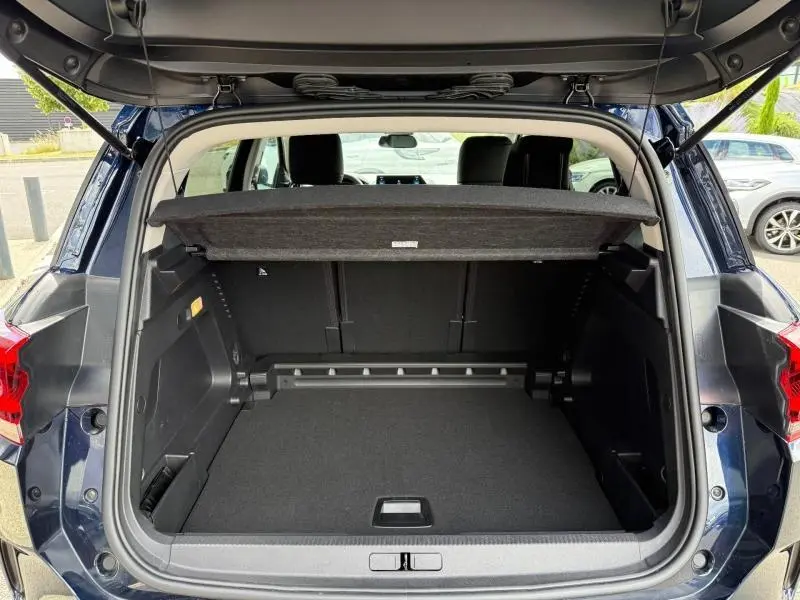 Coffre ouvert vu de l'arrière du Citroën C5 Aircross 2025 bleu, montrant l'espace de chargement et la tablette cache-bagages.