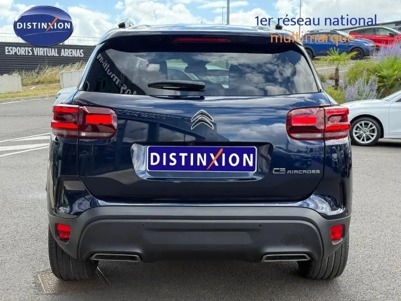 Vue arrière d'un Citroën C5 Aircross 2025 bleu foncé avec feux rouges et logo distinctif sur parking extérieur.