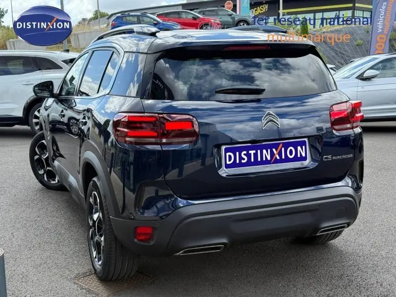 Vue 3/4 arrière droite d'un Citroën C5 Aircross bleu foncé hybride 2025 avec feux arrière LED et jantes noires.