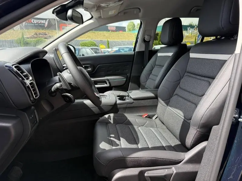 Intérieur du Citroën C5 Aircross 2025 vu côté conducteur, sièges tissu et cuir noir avec surpiqûres grises.