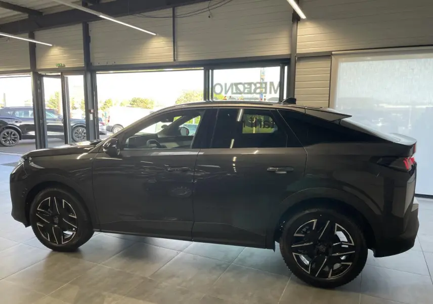 Profil côté gauche du Peugeot 3008 gris foncé hybride 2025 en intérieur, avec jantes alliage 19'' diamantées noires.