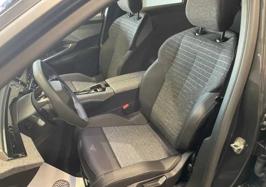 Vue intérieure côté conducteur du Peugeot 3008 2025 gris foncé, sièges tissu gris et cuir noir avec surpiqûres contrastées.