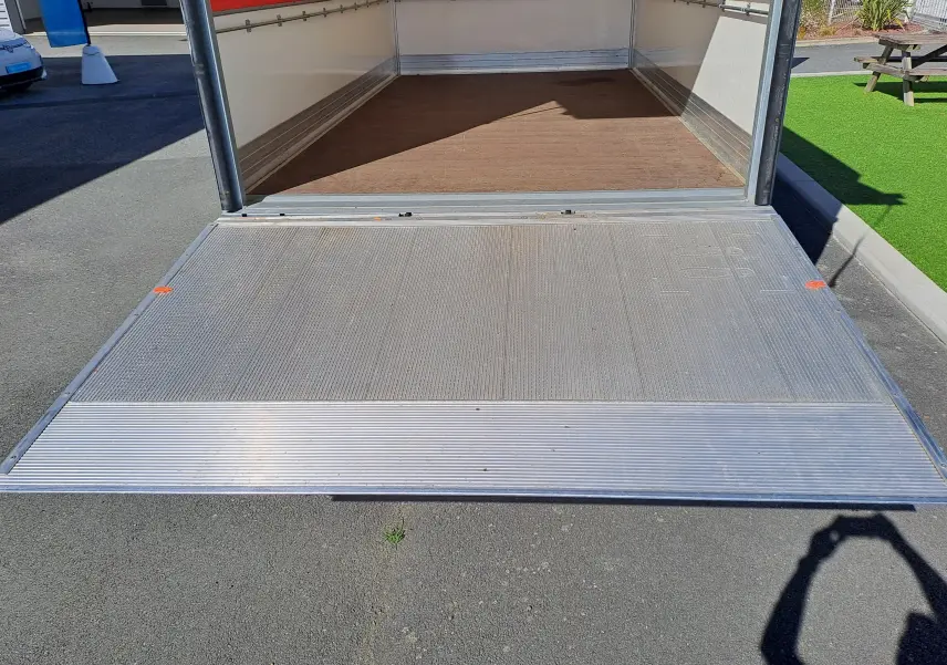 Vue arrière en plan rapproché de la benne ouverte d’un Nissan Interstar châssis cabine blanc, montrant la rampe métallique.