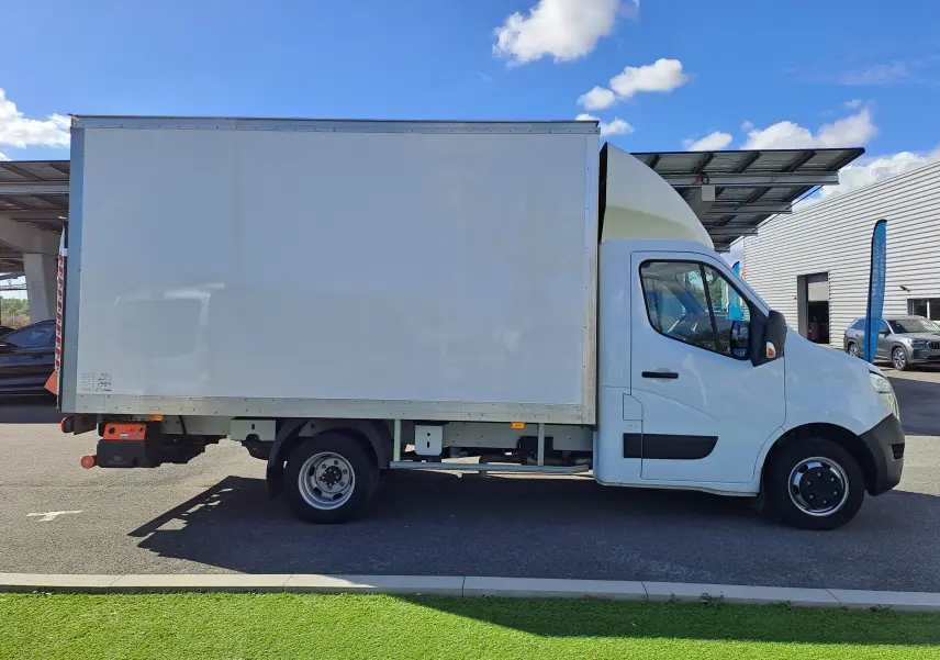 Vue de profil côté droit d’un Nissan Interstar châssis cabine blanc avec caisse fermée sur fond de ciel bleu.