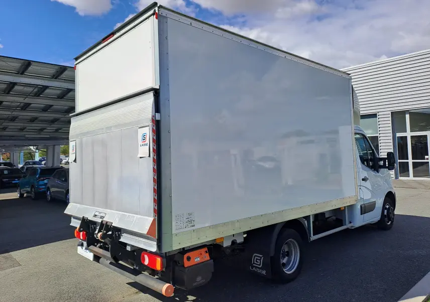 Vue 3/4 arrière droite d’un utilitaire blanc Nissan Interstar Chassis Cabine 2024 avec caisse fermée et hayon élévateur.