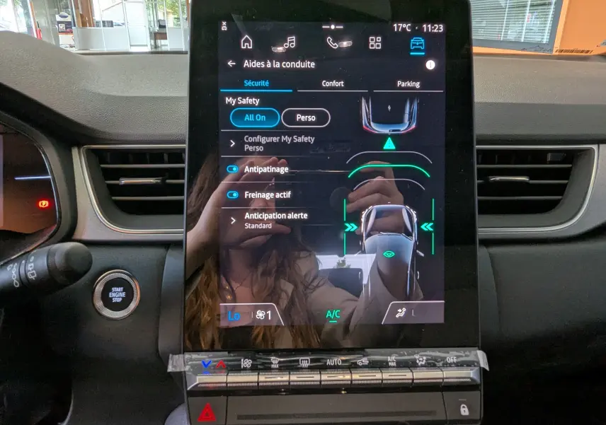 Écran tactile central du Renault Captur E-Tech 2025 affichant les aides à la conduite, avec tableau de bord noir et bouton start/stop.