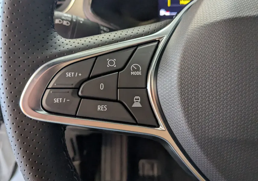 Gros plan sur les commandes du volant côté gauche du Renault Captur E-Tech blanc nacré avec finition noire intérieure.