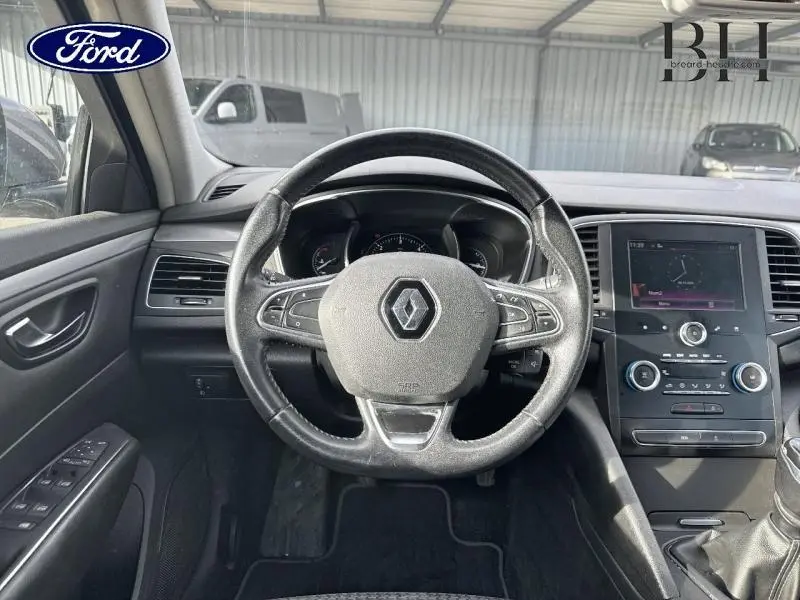 Vue intérieure centrée sur le volant cuir multifonction d'une Renault Talisman gris Cassiopée avec tableau de bord et écran tactile.