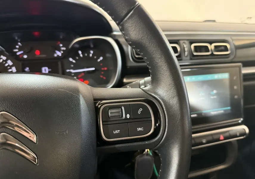 Gros plan sur le volant cuir et le tableau de bord tactile de la Citroën C3 gris clair, version Shine Business.