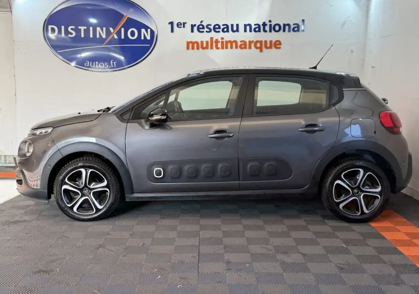 Profil côté gauche d'une Citroën C3 gris clair avec protections latérales noires et jantes alliage distinctives.