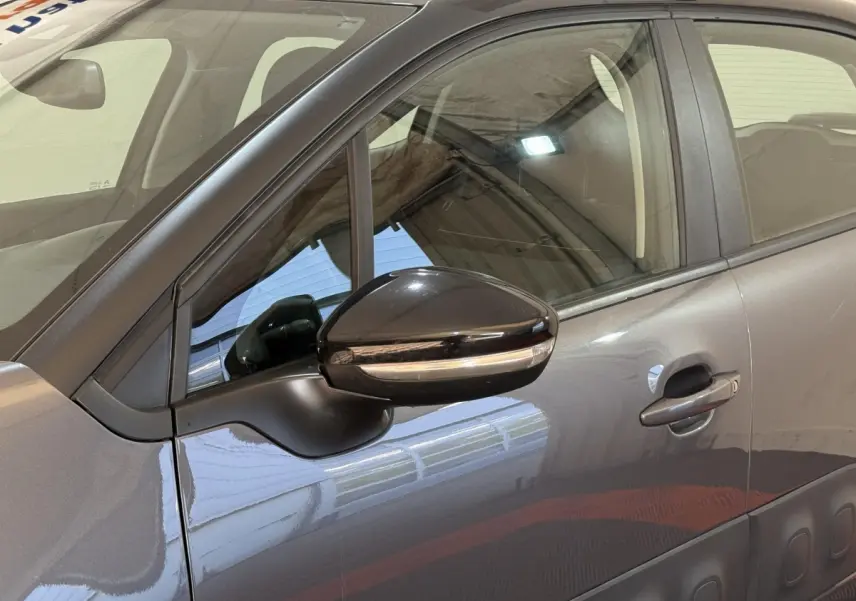 Vue côté gauche rapprochée d'une Citroën C3 gris clair avec rétroviseur noir brillant et poignées ton caisse.