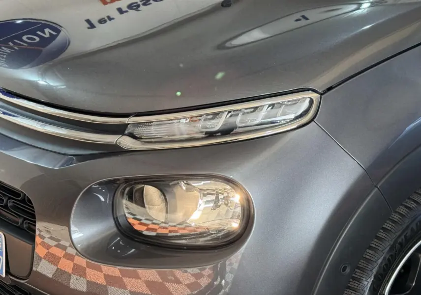 Gros plan sur le phare avant droit d'une Citroën C3 gris clair, mettant en valeur ses feux LED et la carrosserie lisse.