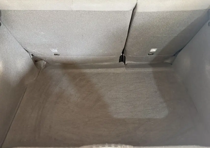 Vue plongeante sur le coffre spacieux et propre de la Citroën C3 gris clair avec banquette arrière rabattue.