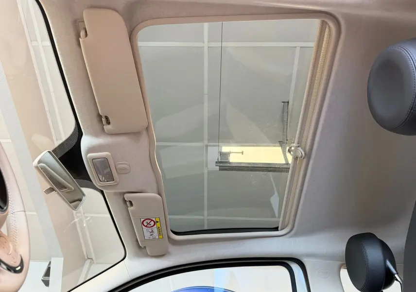 Vue intérieure du toit ouvrant panoramique de la Fiat 500 blanche Dolcevita 2022, avec appuie-tête noir visible.
