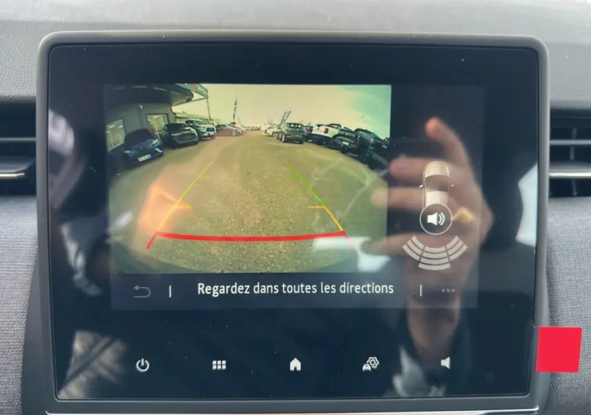 Écran de la caméra de recul de la Renault Clio gris schiste, affichant la vue arrière avec lignes de guidage colorées.