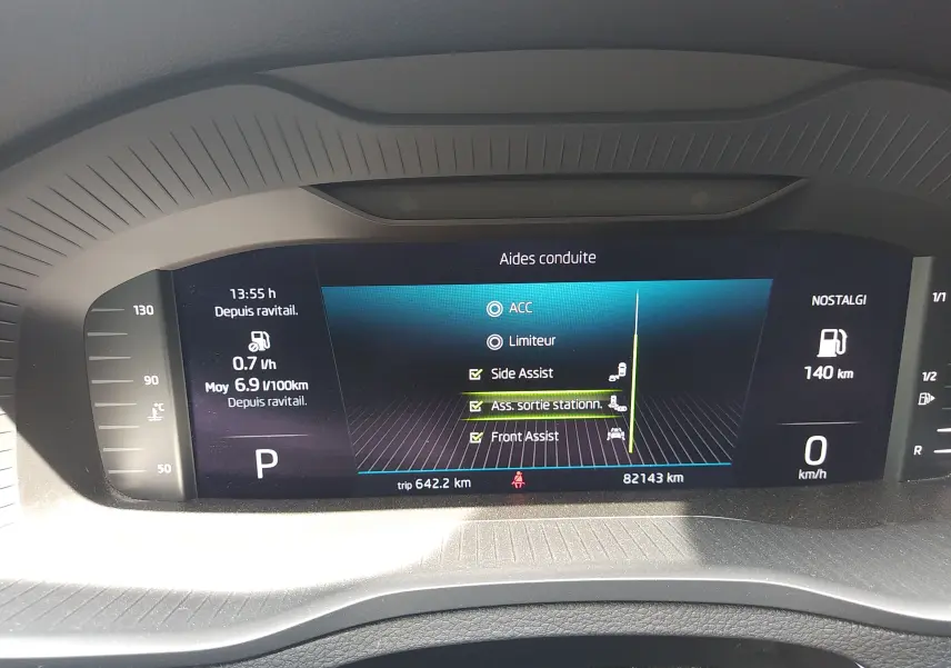 Tableau de bord numérique du Skoda Karoq gris 2022 montrant les aides à la conduite et l'affichage de consommation.