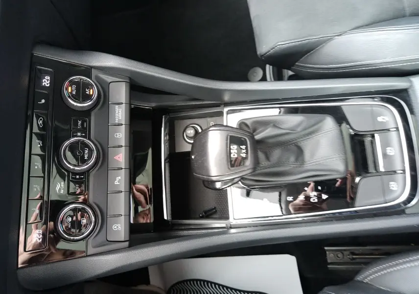 Vue plongeante sur la console centrale noire du Skoda Karoq gris, mettant en valeur le levier DSG 4x4 et les commandes de climatisation.