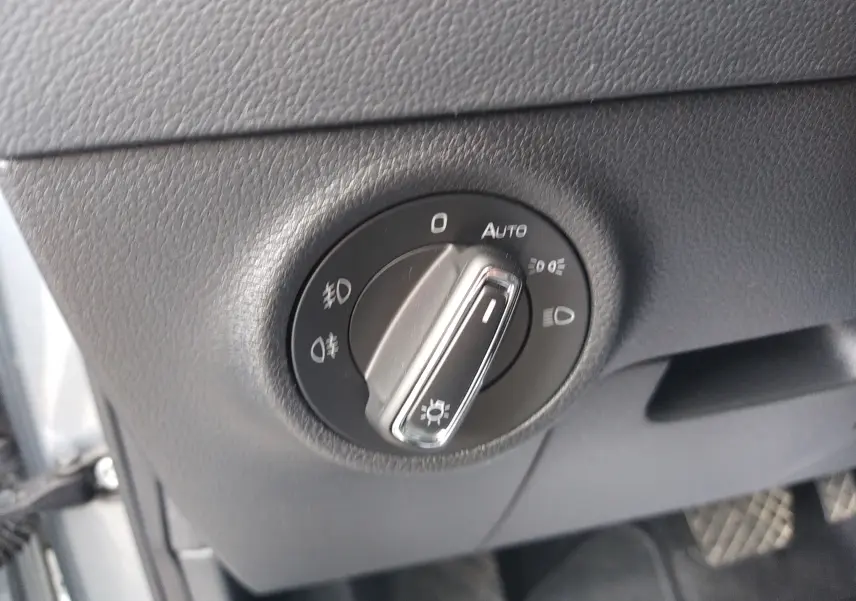 Gros plan sur le bouton de commande des phares dans l'habitacle gris du Skoda Karoq 2022 côté conducteur.