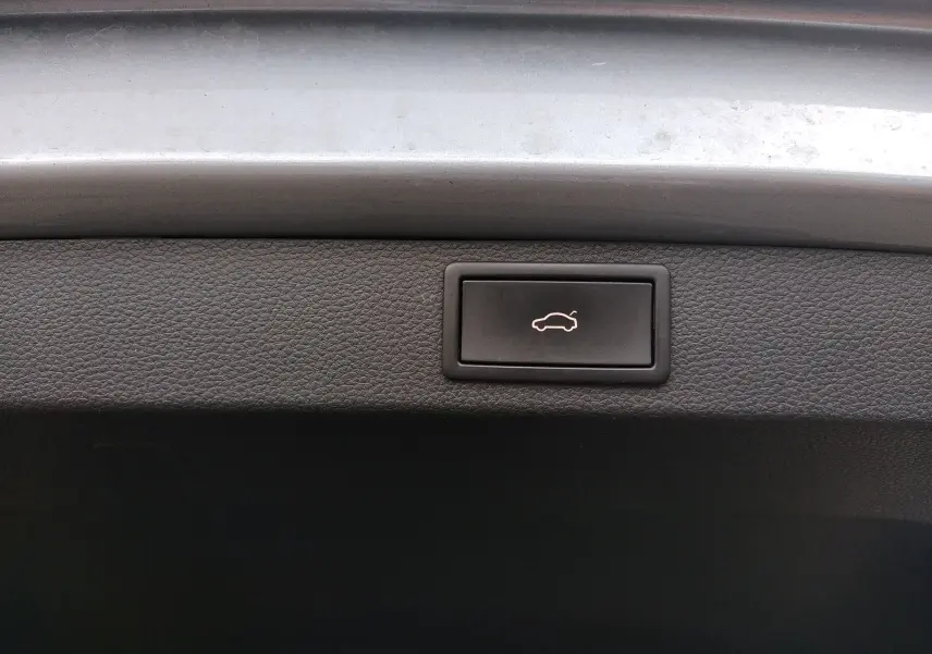 Bouton d'ouverture électrique du hayon sur le coffre intérieur d'un Skoda Karoq gris 2022.