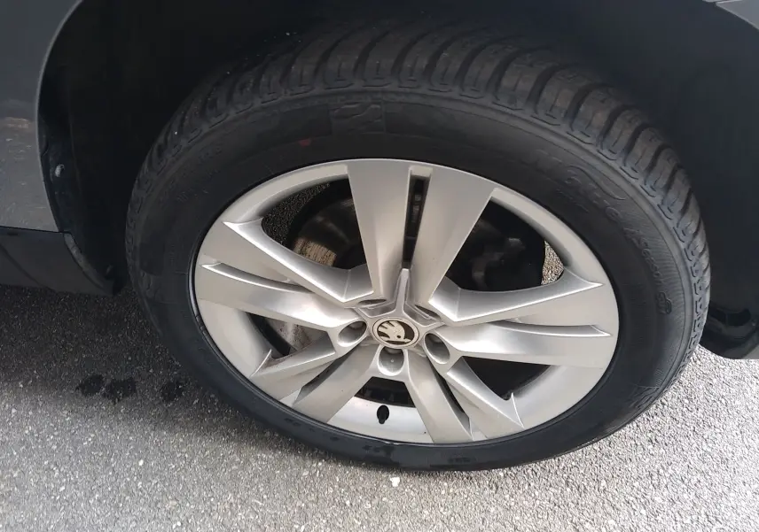 Gros plan sur la roue avant droite d’un Skoda Karoq gris, mettant en valeur la jante alliage 5 branches doubles.