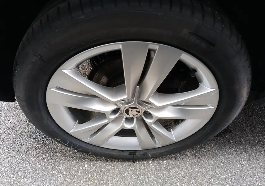 Gros plan sur la jante alliage argentée à 5 doubles branches du Skoda Karoq gris, avec logo central visible.