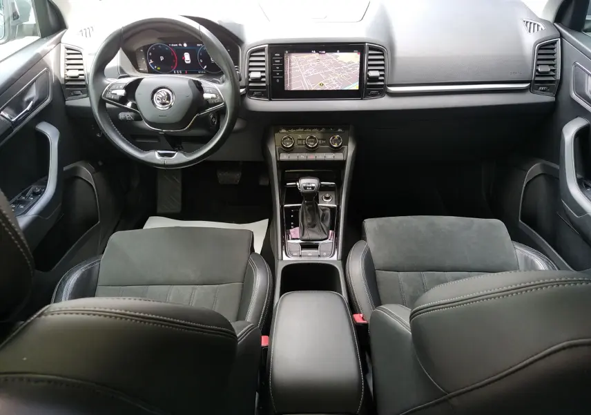 Vue intérieure avant du Skoda Karoq gris 2022, avec tableau de bord digital, écran central tactile et sièges en cuir alcantara.