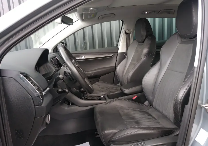 Vue intérieure côté conducteur du Skoda Karoq gris 2022, sièges en cuir et alcantara noirs avec coutures contrastées.