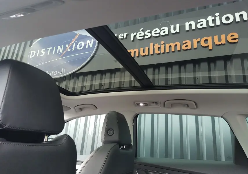 Vue intérieure du SKODA KAROQ gris 2022, mettant en valeur le toit panoramique et les sièges en cuir noir.