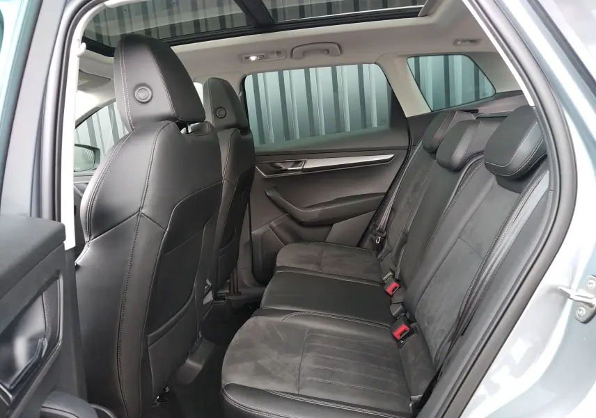 Vue intérieure côté droit des sièges arrière en cuir noir et alcantara du Skoda Karoq gris 2022 avec toit ouvrant panoramique.