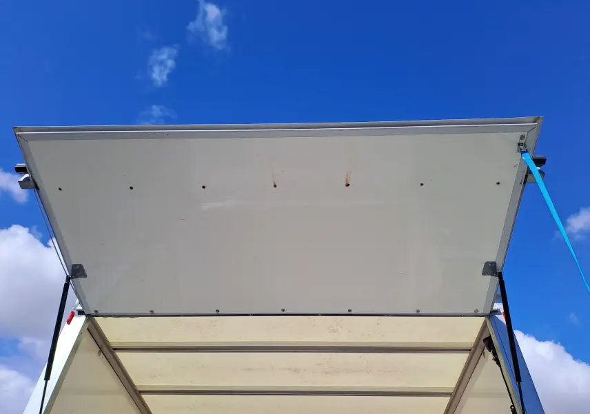 Vue de dessous de la porte arrière blanche ouverte du Nissan Interstar Châssis Cabine 2024, avec ciel bleu en arrière-plan.