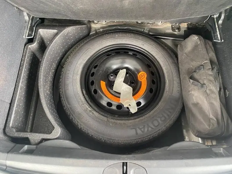 Vue plongeante sur la roue de secours noire et son rangement dans le coffre du Fiat 500X 2018 noir Lounge.