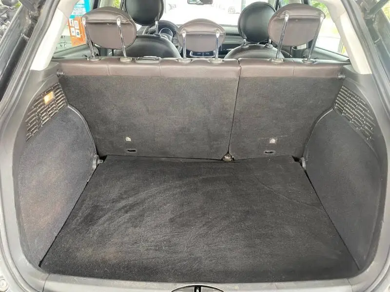 Coffre spacieux vu de l'arrière d'une Fiat 500X noire, banquette arrière en cuir noir rabattue partiellement.