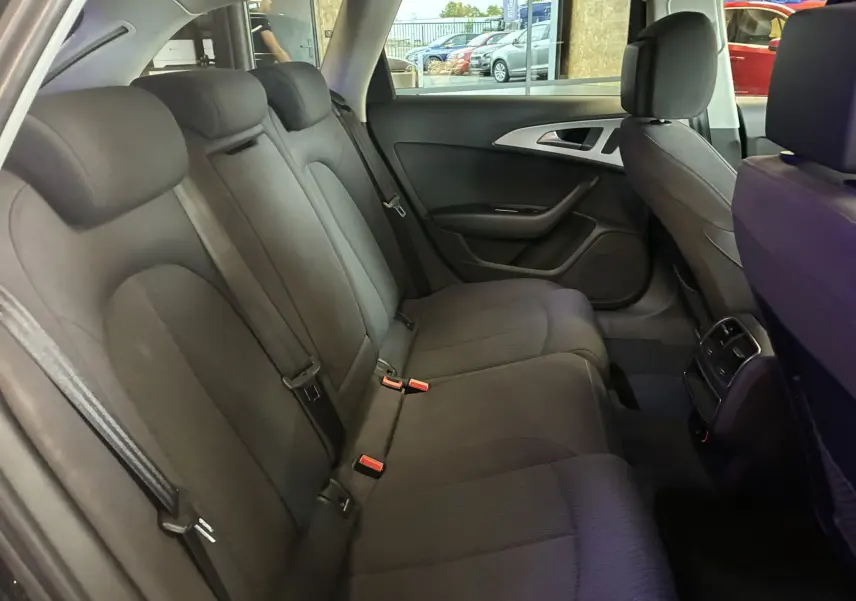 Vue intérieure côté droit des sièges arrière noirs en tissu de l'Audi A6 Avant 2017, avec ceintures et aérateurs centraux visibles.