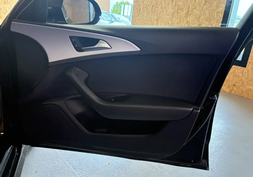 Vue intérieure côté gauche de la porte noire d'une Audi A6 Avant 2017 avec garniture sobre et poignée intégrée.