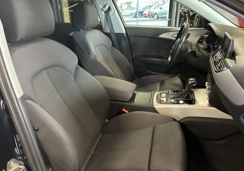 Intérieur noir en tissu de l'Audi A6 Avant 2017, vue côté conducteur avec console centrale et volant multifonction.