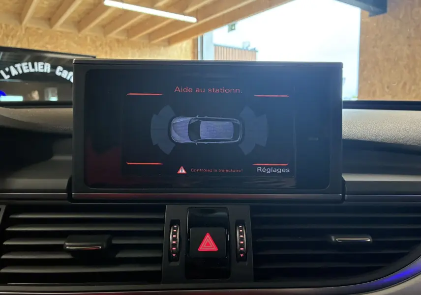 Écran central de l'Audi A6 Avant 2017 montrant l'aide au stationnement avec tableau de bord noir et commandes visibles.