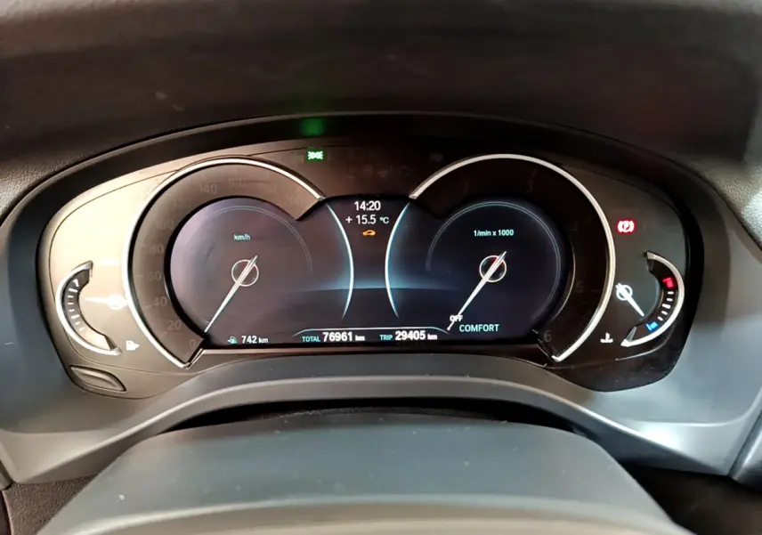 Vue rapprochée du tableau de bord numérique de la BMW X3 noire, affichant vitesse, compte-tours et température extérieure.