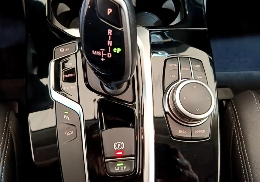 Vue rapprochée de la console centrale noire brillante du BMW X3 xDrive20d 2020 avec levier de vitesses et commandes multimédia.