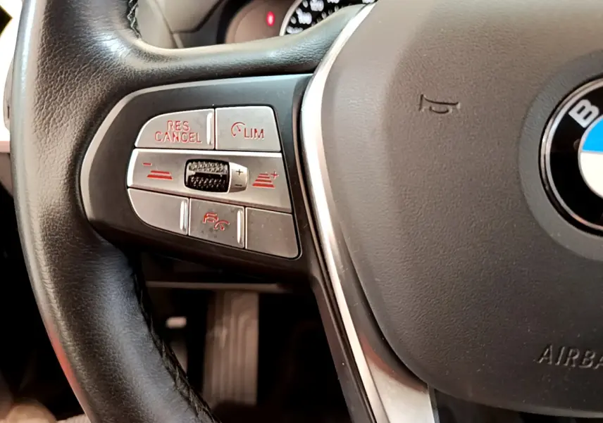 Gros plan sur la partie gauche du volant cuir noir du BMW X3 xDrive20d 2020 avec commandes de régulateur de vitesse.