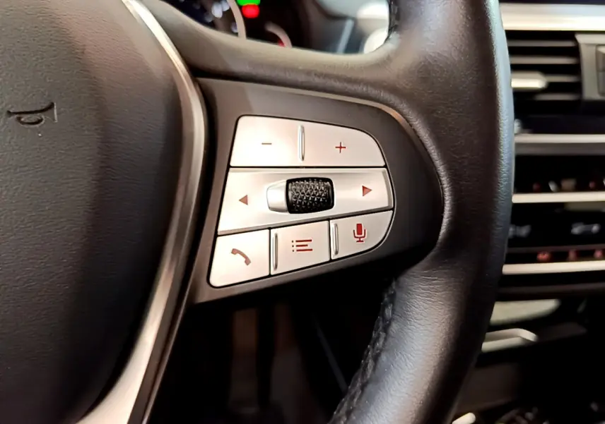Gros plan sur les commandes multifonctions côté gauche du volant cuir noir du BMW X3 xDrive20d 2020.