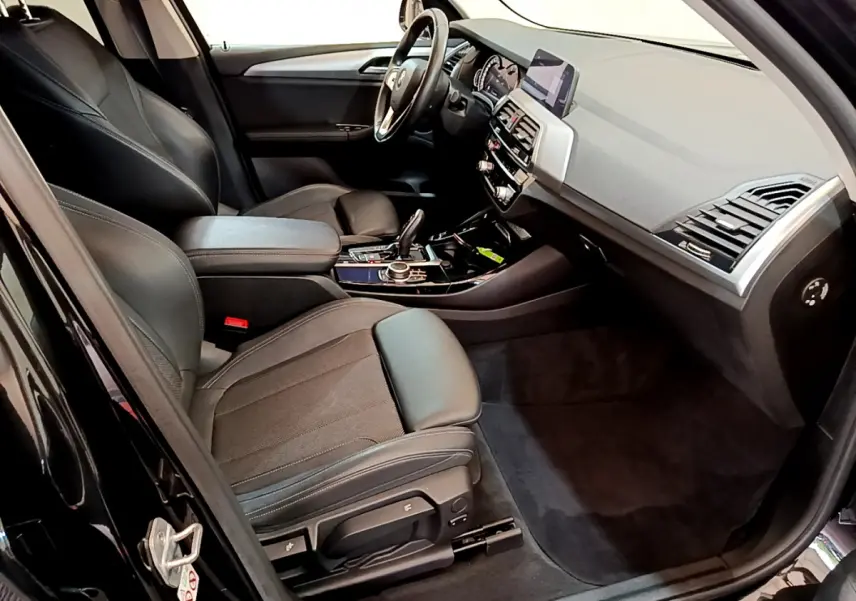 Intérieur avant droit BMW X3 xDrive20d 2020 noir, sièges cuir, tableau de bord moderne avec écran central et console élégante.