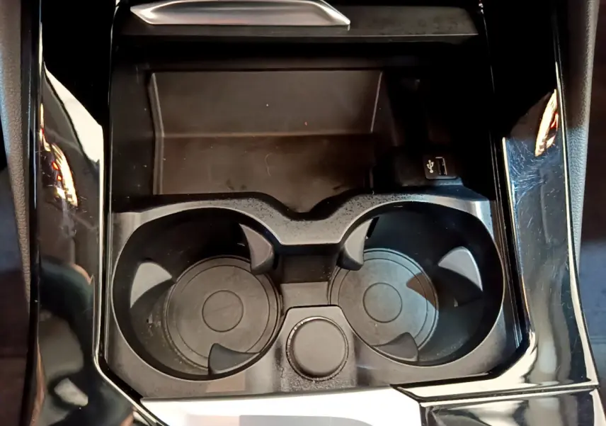 Gros plan sur les porte-gobelets noirs et prise USB dans la console centrale du BMW X3 xDrive20d Lounge 2020.