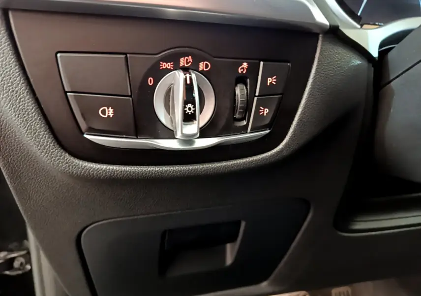 Gros plan sur le panneau de commande des phares du BMW X3 xDrive20d 2020, intérieur noir avec commandes rétroéclairées rouges