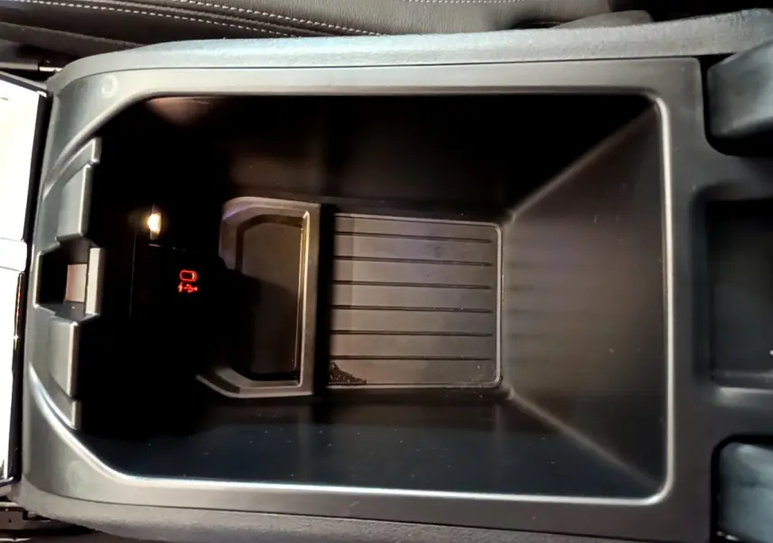 Vue rapprochée du rangement central intérieur du BMW X3 noir, avec éclairage et indicateur rouge visible.