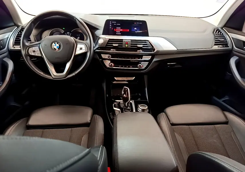 Vue intérieure frontale du tableau de bord et volant cuir noir du BMW X3 xDrive20d 2020 avec écran tactile central et console moderne.