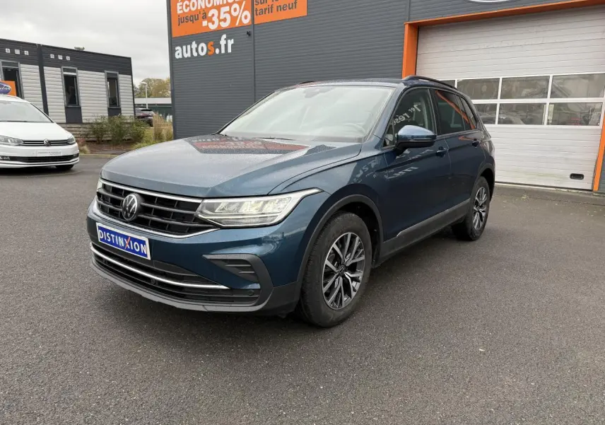Volkswagen Tiguan bleu nuit métallisé vu en 3/4 avant droit avec jantes alliage et feux LED allumés.