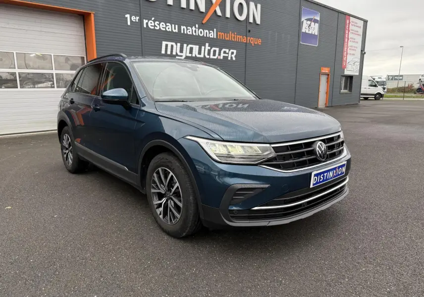 Volkswagen Tiguan 2022 bleu Nightshade en 3/4 avant droit, avec jantes alliage et phares LED allumés.