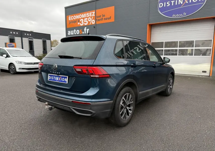 Volkswagen Tiguan bleu nuit métallisé vu en 3/4 arrière droit avec crochet d'attelage et jantes alliage 17 pouces.
