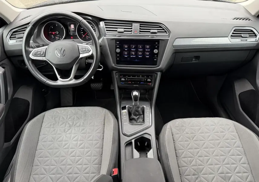 Vue intérieure du tableau de bord et des sièges gris tissu du Volkswagen Tiguan 2022 avec écran tactile central et volant multifonctions.